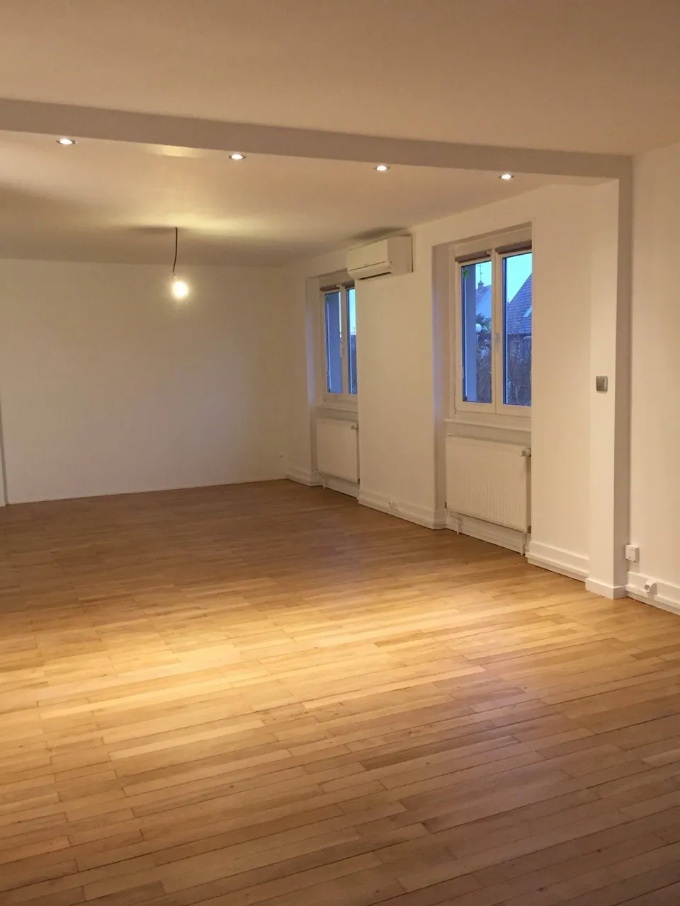 Ponçage de parquet à Wittenheim — Pièce rénovée : parquet clair, murs blancs et radiateurs reposés.