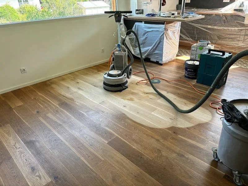 Ponceuse monobrosse reliée à un aspirateur sur un chantier de ponçage de parquet