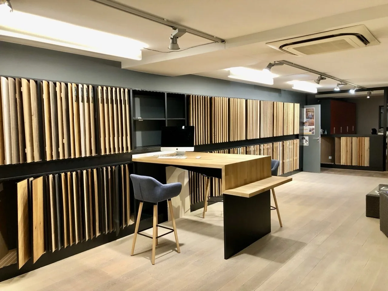 Échantillons de revêtements de sol en bois exposés dans un showroom avec un parquet clair posé