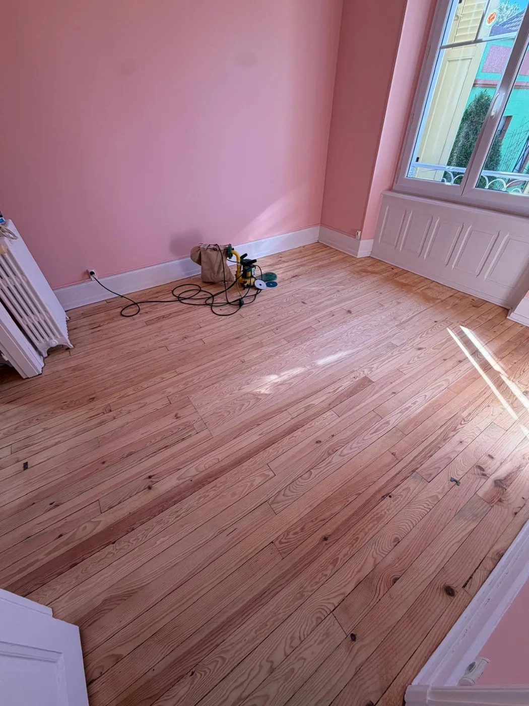 Préparation du parquet dans la pièce aux murs roses, avant finition.