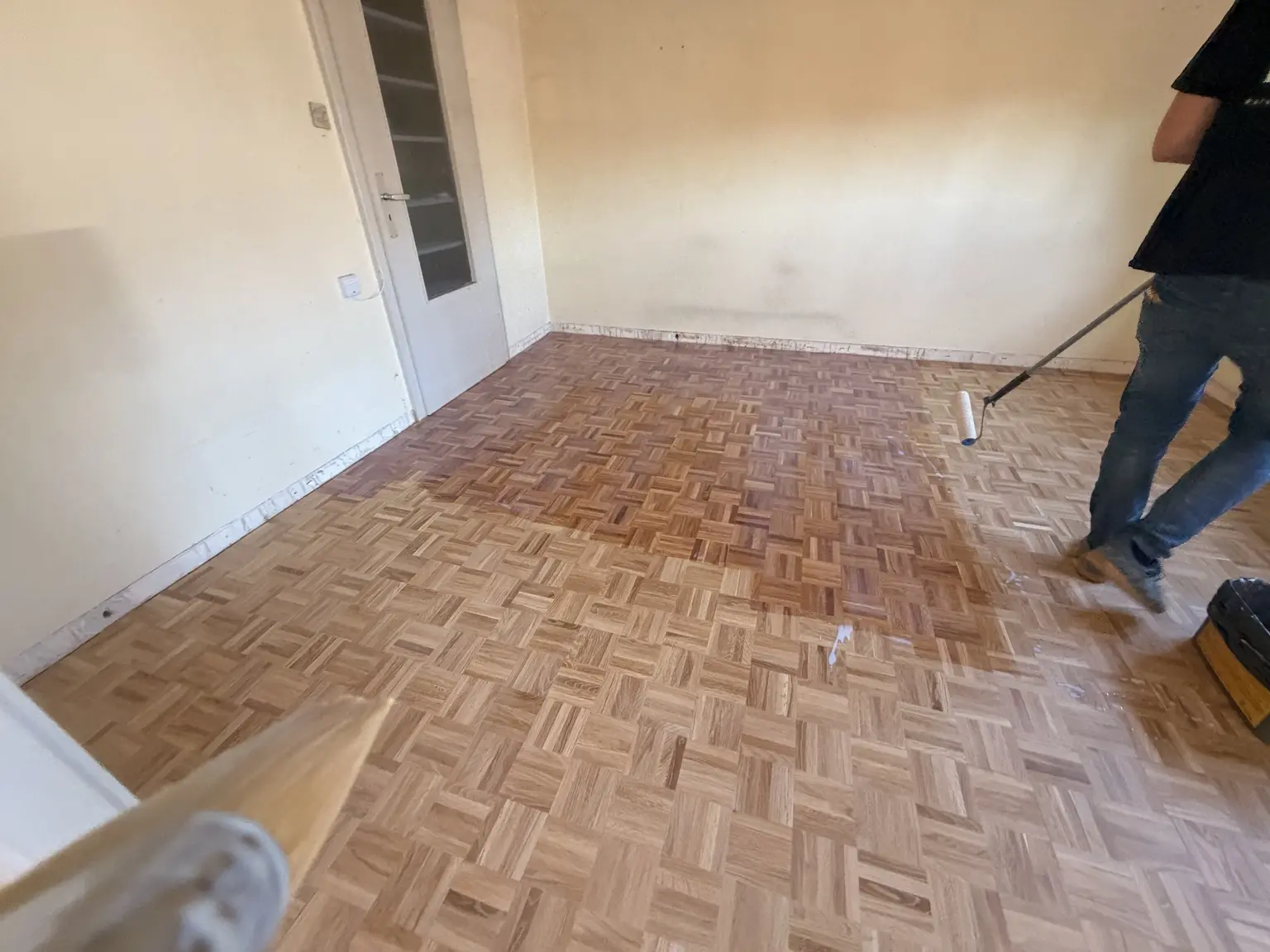 Application au rouleau de la première couche sur le parquet mosaïque à Colmar