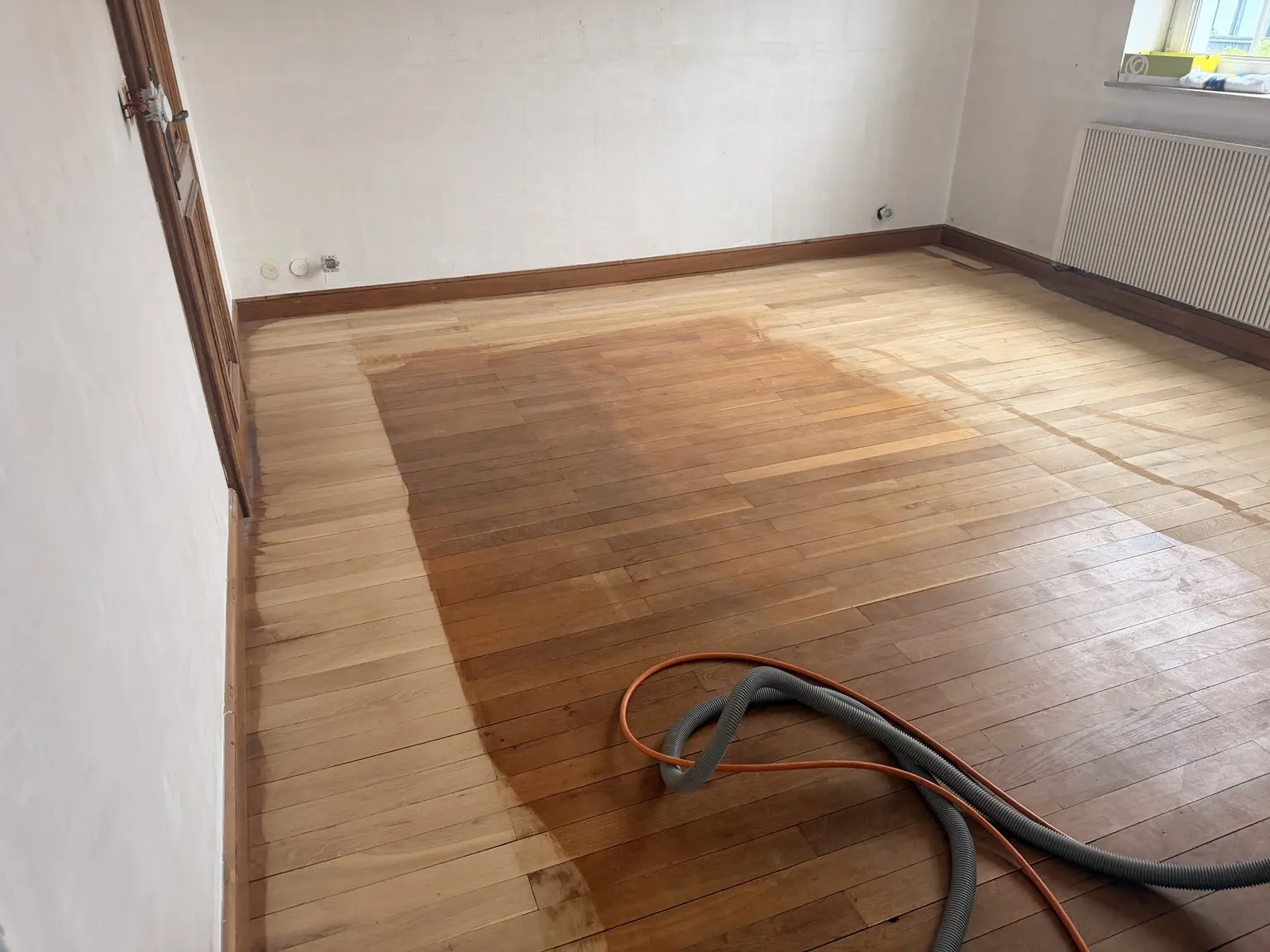 Différence visible entre le parquet encore ciré et la partie remise à blanc pendant le ponçage