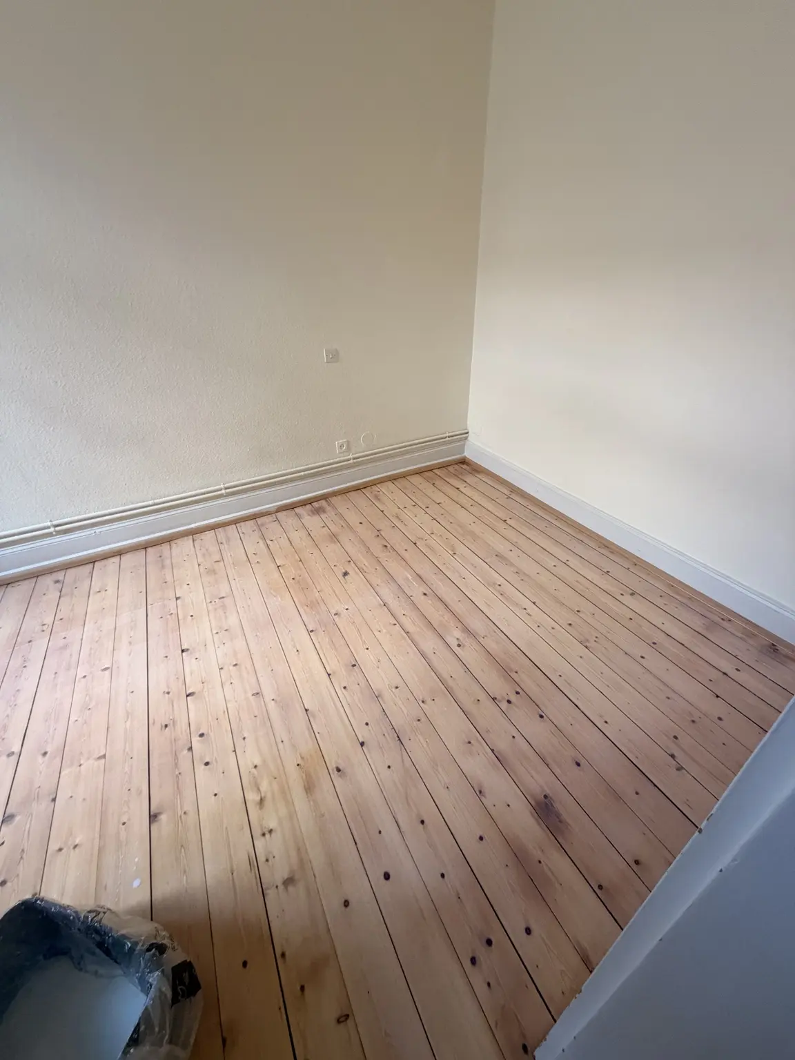 Vue du parquet en sapin rénové le long du mur dans la chambre