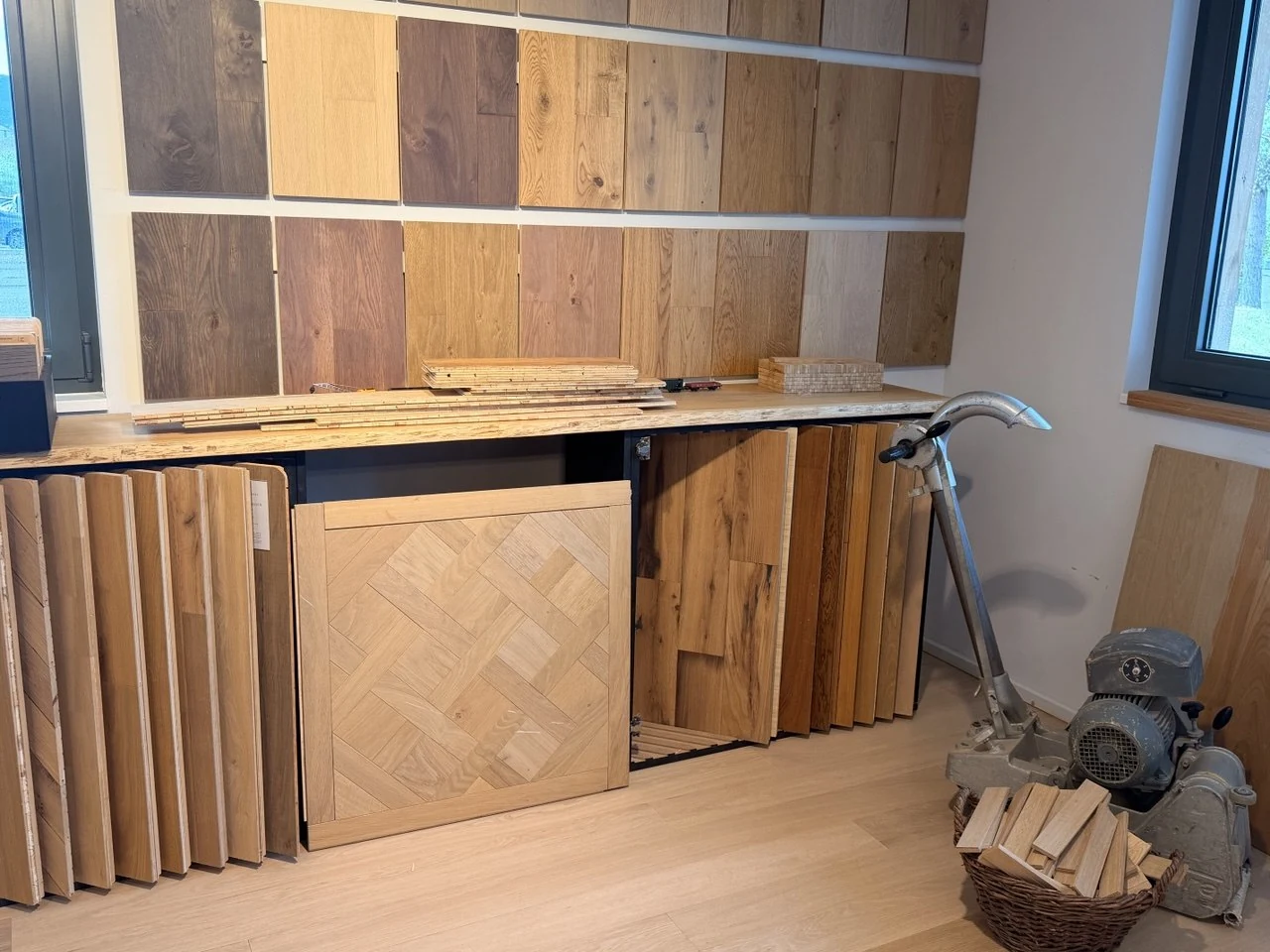 Échantillons et panneaux de parquet exposés dans notre showroom, avec une ponceuse professionnelle.