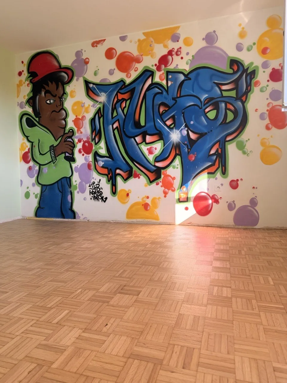 Pièce vide avec parquet mosaïque fraîchement vitrifié et fresque murale, plinthes non posées